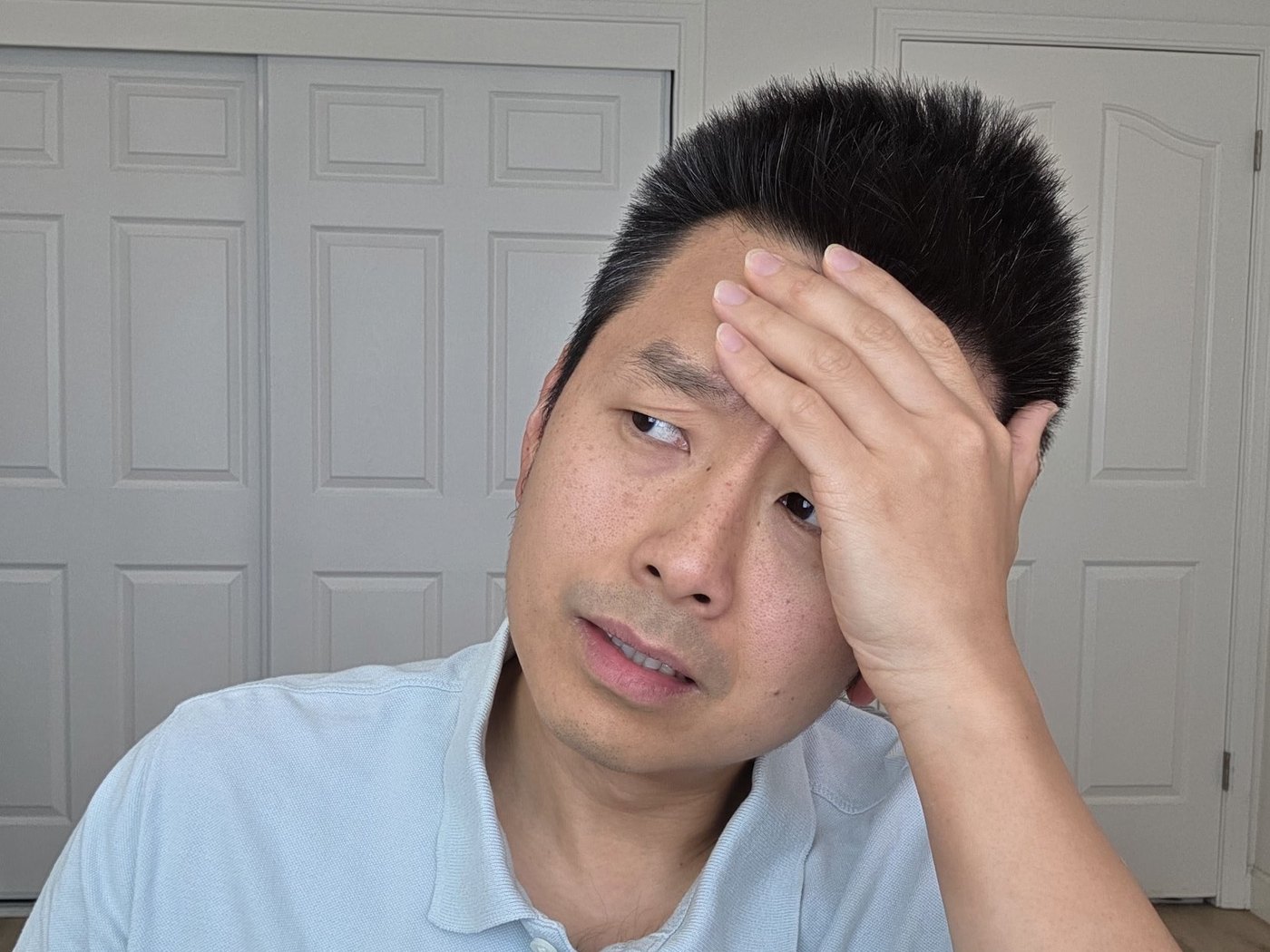 Wen Fan, MA, LMFT, with a hand on his forehead and a wry, puzzled expression