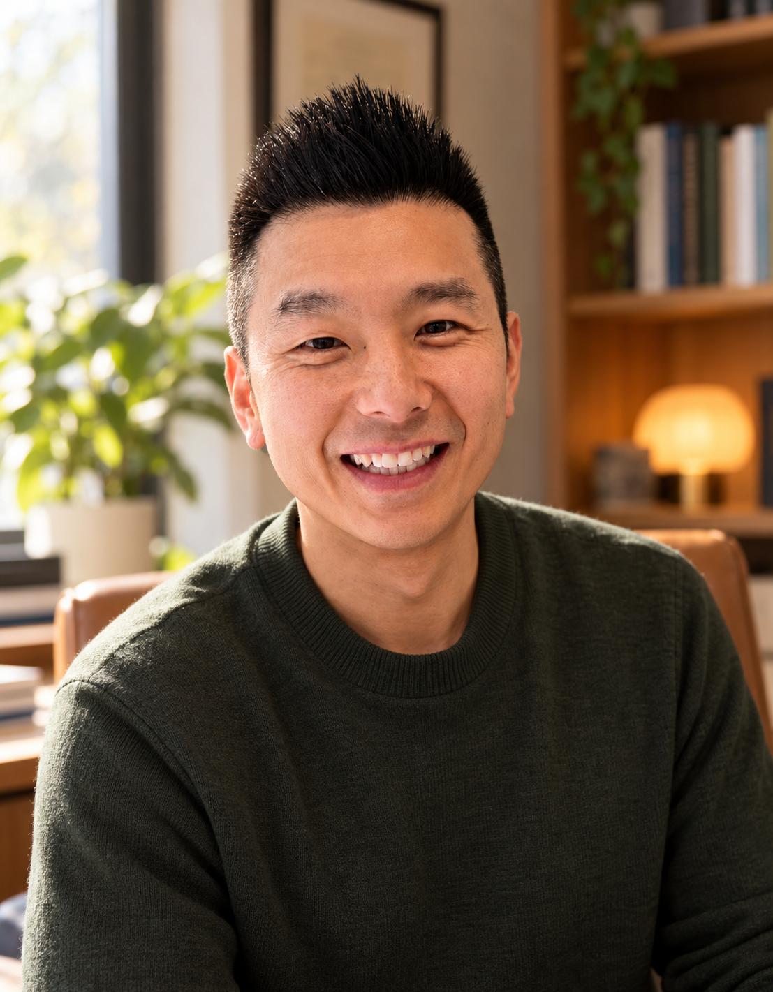 Portrait of Wen Fan, smiling, in a warmly lit office